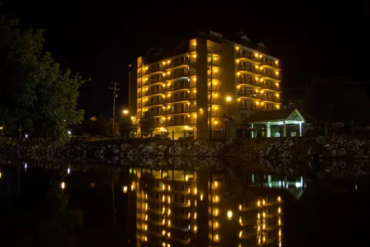 Riverside Tower lit up at night, reflected in the river